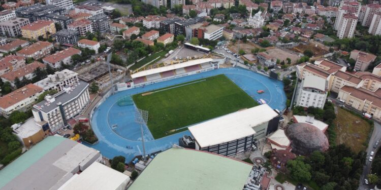 Havadan çekilmiş, mavi tartan pistli ve yeşil sahanlı bir spor kompleksi.