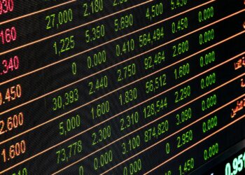 Siyah elektronik ekranda yeşil ve kırmızı renkli borsa verileri yer alıyor.