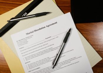 Ahşap masa üzerinde duran Marital Dissolution Agreement adlı hukuki belge ve kalemler.