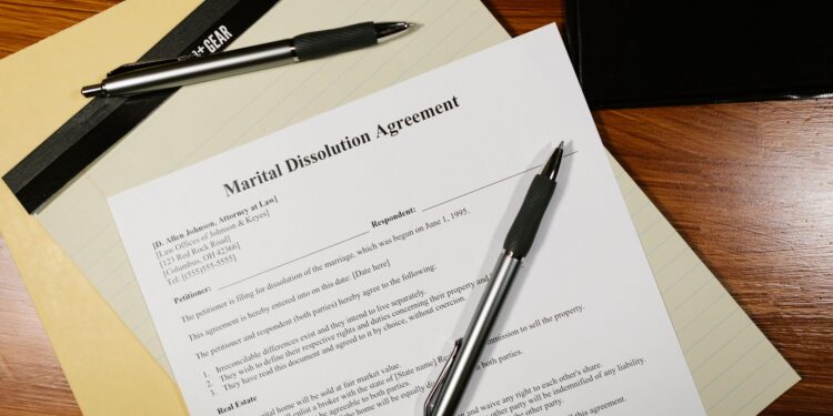 Ahşap masa üzerinde duran Marital Dissolution Agreement adlı hukuki belge ve kalemler.