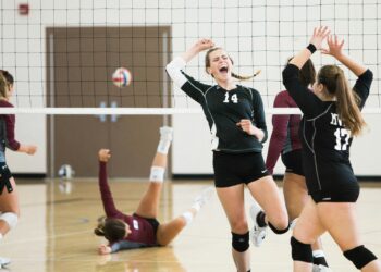 Salonda sayı sevinci yaşayan siyah formalı profesyonel kadın voleybol takımı