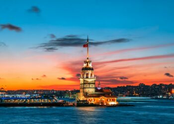 İstanbul'da gün batımı manzarası eşliğinde Kız Kulesi ve Boğaz'daki tekneler.