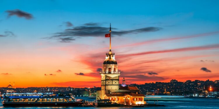 İstanbul'da gün batımı manzarası eşliğinde Kız Kulesi ve Boğaz'daki tekneler.