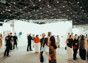 Geniş bir sanat galerisinde gezinen kalabalık sanatseverler ve sergilenen tablolar