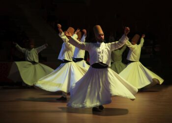 Sema gösterisi yapan beyaz giysili semazenlerin sahnedeki performansı.