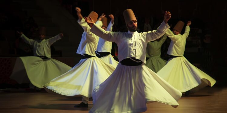 Sema gösterisi yapan beyaz giysili semazenlerin sahnedeki performansı.