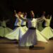 Sema gösterisi yapan beyaz giysili semazenlerin sahnedeki performansı.