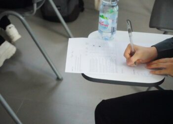 Sınav masasında oturan öğrenci önündeki test kağıdına cevaplar yazıyor.