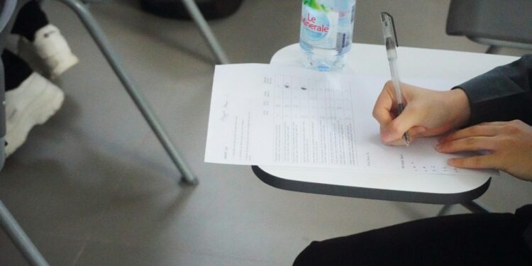 Sınav masasında oturan öğrenci önündeki test kağıdına cevaplar yazıyor.