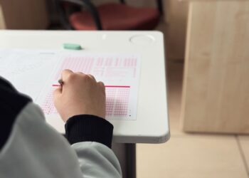Sınavda optik form dolduran bir öğrencinin eli ve masası.