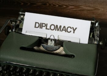Ahşap masanın üzerinde 'DIPLOMACY' yazısı bulunan yeşil renkli daktilo.