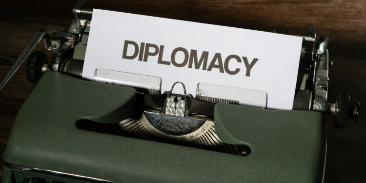 Ahşap masanın üzerinde 'DIPLOMACY' yazısı bulunan yeşil renkli daktilo.