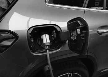 Gri renkli bir elektrikli otomobilin şarj kapağı açık ve şarj ediliyor.